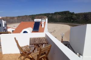 two chairs and a table on a balcony with a beach at AzuldoMar - Beach House in Odeceixe