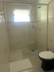 La salle de bains est pourvue d'une douche en verre et de toilettes. dans l'établissement Sítio Maranata Vale das Montanhas, à Monte Alegre do Sul