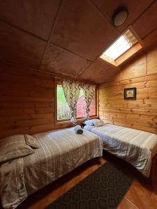 two beds in a log cabin with a window at CASA LA KOCHA, Cabin, Hostal en la Laguna de la Cocha in El Encano