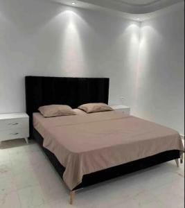 um quarto com uma cama grande e uma cabeceira preta em Appartement haut standing 170 m2 em Tunes