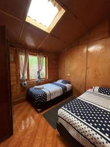 two beds in a room with a skylight at CASA LA KOCHA, Cabin, Hostal en la Laguna de la Cocha in El Encano