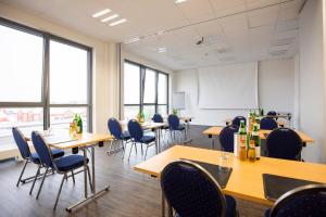 uma sala de aula com mesas, cadeiras e janelas em Viva Hotel Lübeck em Lübeck