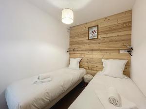 twee bedden in een kamer met houten wanden bij AMBRE BLANCHE A106 - Les Gets - Centre village in Les Gets