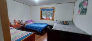 Habitación con 2 camas y ventana en casa de campo, en Villarrica