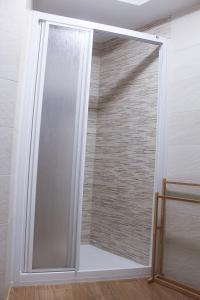 uma porta de duche em vidro num quarto com uma parede de tijolos em Casa Gelina em Gijón