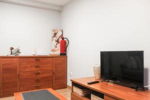 uma sala de estar com uma televisão de ecrã plano e uma cómoda em madeira em Casa Gelina em Gijón