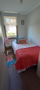 Un dormitorio con una cama con una colcha roja y una ventana en Departamento Cumbres de Miramar, en San Antonio