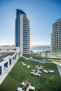 a resort with a lawn with tables and chairs and buildings at Pearls of Umhlanga Apts in Durban