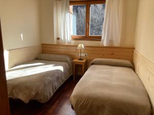 two beds in a room with a window at Apartament Vall in Rialp