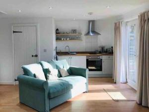 een woonkamer met een blauwe bank en een keuken bij Relaxing studio and garden in St Hilary in Cowbridge