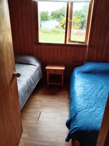 una piccola camera con due letti e una finestra di Cabañas Rayen Ancud ad Ancud