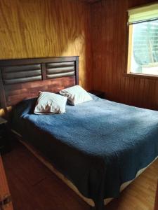 1 dormitorio con 1 cama con 2 almohadas en Cabañas Rayen Ancud, en Ancud