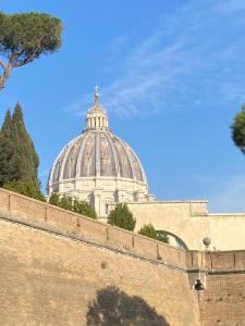 un edificio detrás de una pared con una cúpula en el fondo en APT a due passi da San Pietro, en Roma