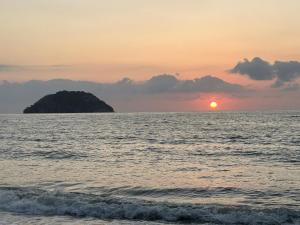 um pôr do sol sobre o oceano com uma pequena ilha em Casa Moka em Peñita de Jaltemba