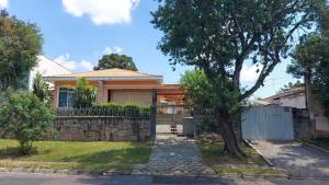 a house with a fence and a tree at Casa de hóspedes 436 in Curitiba