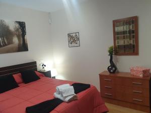 1 dormitorio con cama roja y tocador de madera en Piso Alerín II, en Silleda