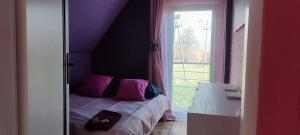 Un dormitorio con una cama con almohadas rosas y una ventana en Ostoja Karkonoska, en Podgórzyn