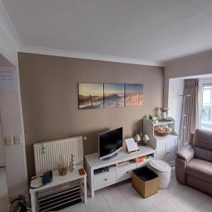 ein Wohnzimmer mit einem TV und einem Sofa in der Unterkunft Zijdezeezicht Martiny 0202 in Middelkerke