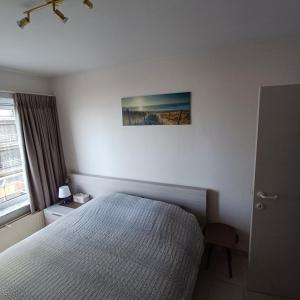 ein Schlafzimmer mit einem Bett und einem Bild an der Wand in der Unterkunft Zijdezeezicht Martiny 0202 in Middelkerke