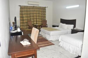 Habitación de hotel con 2 camas y mesa en Rising House, en Islamabad