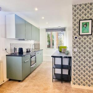 uma cozinha com armários verdes e uma bancada em Maison Mayel - Logement Entier - Domaine Privé Résidentiel Chic & Nature em Lamorlaye