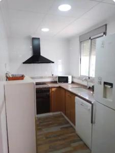 uma cozinha com um frigorífico branco e um lavatório em La Caseta de Jose em Mareny Barraquetas