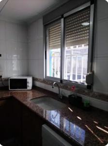 encimera de cocina con fregadero y ventana en La Caseta de Jose, en Mareny Barraquetas