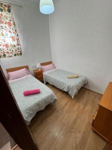 ヘレス・デ・ラ・フロンテーラにあるApartamentos Porvera Jerezのピンクの枕が備わる小さな部屋のベッド2台