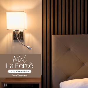 a lamp on a wall next to a bed at Hotel La Fertè in Asti