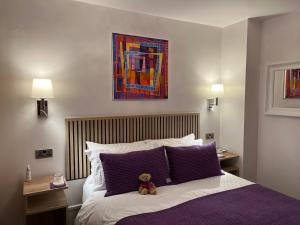 a teddy bear sitting on a bed with purple pillows at Ceol na Mara Guest House in Tarbert
