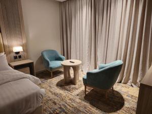 SEAGULL HOTEl في أملج: غرفه فندقيه بسرير وكرسيين وطاولة