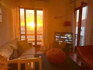 a living room with a couch and a television with a sunset at M illumino d immenso - Un risveglio in mare MONEGLIA APARTMENTS in Moneglia