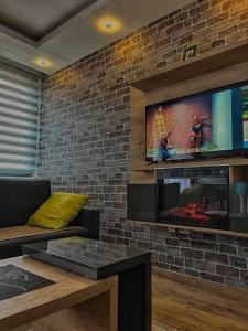 Apartman LED-Treska في كوباونيك: غرفة معيشة مع تلفزيون على جدار من الطوب
