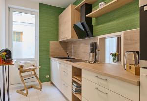 eine Küche mit grünen Wänden und einer Theke mit einem Stuhl in der Unterkunft Schelfstadtoase in Schwerin