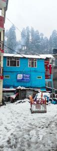 un edificio azul con nieve delante en Tiny Spot Hostel, en Manali