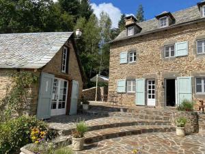 an old stone house with a stone staircase in front of it at La Roulière en Aubrac in Montpeyroux