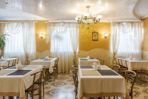 a restaurant with white tables and chairs and a chandelier at Вілла ЮРАН Східниця in Skhidnitsa +111 photos