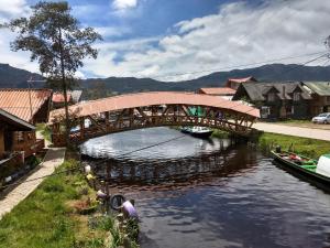 a wooden bridge over a river with boats in it at CASA LA KOCHA, Cabin, Hostal en la Laguna de la Cocha in El Encano