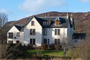 a large white house with a hill in the background at Kilchoan Hotel in Kilchoan