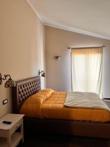 a bedroom with a bed with an orange blanket and a window at Residence La Torre in Acerenza