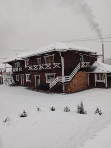ein schneebedecktes Gebäude mit Bäumen davor in der Unterkunft ГІРСЬКІ ПОДОРОЖі in Slawske
