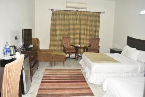 Habitación de hotel con 2 camas, mesa y sillas en Rising House, en Islamabad