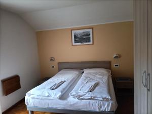 Un dormitorio con una cama con sábanas blancas. en ALBERGO AL LAGO, en Imer