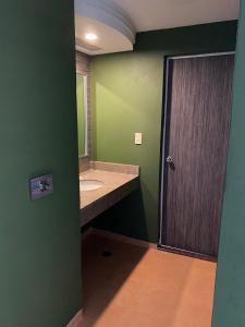 a green bathroom with a sink and a mirror at Hotel Gran Vía in Mexico City