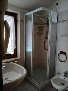 y baño con ducha y lavamanos. en ALBERGO AL LAGO, en Imer