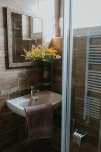 a bathroom with a sink and a mirror and flowers at Drevenice Horné Kysucé in Vysoká nad Kysucou