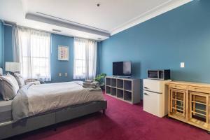 Schlafzimmer mit einem Bett und einem TV sowie blauen Wänden in der Unterkunft Urban Nest Studios in Halifax