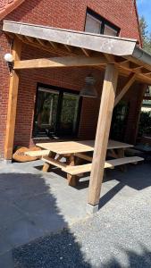 een houten picknicktafel voor een bakstenen gebouw bij Villa BOSgeluk, riante rust bij BOS7 op de Veluwe. in Putten