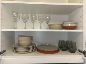 a shelf with plates and wine glasses in a kitchen at New Stylish 2-Bed Retreat in Central Windsor in Windsor