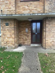 a brick building with a door and a grass yard at New Stylish 2-Bed Retreat in Central Windsor in Windsor